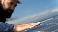 Mann streicht mit Hand über Solaranlage